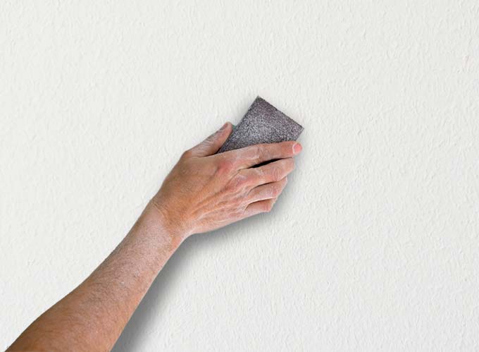 Use papel de lija para lijar la superficie de la pared. nivelación de  superficies, trabajo en el interior de la casa.